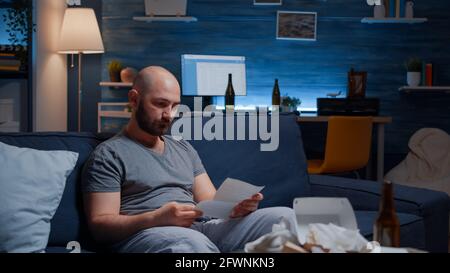 Desperate, depressed, helpless frustrated man reading paper letter with banking bills crying having notification, eviction notice. Shocked male by financial problems bankruptcy, unexpected bad news Stock Photo