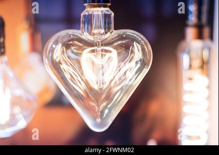 Many differently shaped incandescent bulbs are suspended in the dark Stock Photo
