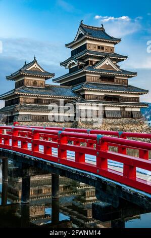 Matsumoto Castle and the red wooden bridge crossing the moat. Nagano Prefecture on Honshu Island, Japan. Stock Photo