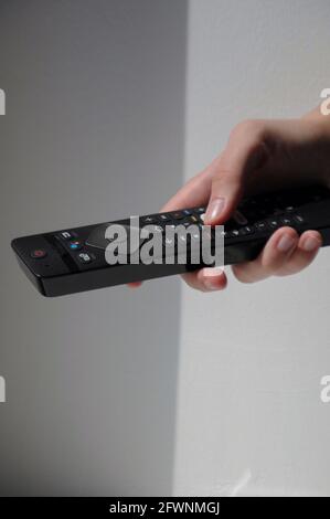 Hand with black tv remote control on white background Stock Photo