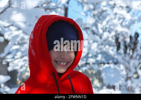 Outdoor winter portrait of little healthy happy baby child walking in the park on cold day with snow and snowfall. Selective focus Stock Photo