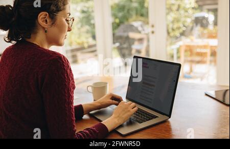 Woman sitting at table and using laptop. Female blogger working from home. Stock Photo