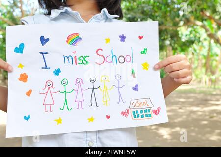 Child holding I miss School message on paper. Sadness in homeschooling during covid-19 pandemic concept. Stock Photo