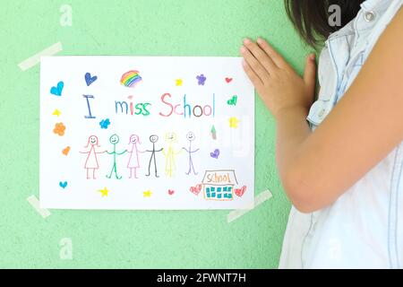 Child holding I miss School message on paper. Sadness in homeschooling during covid-19 pandemic concept. Stock Photo