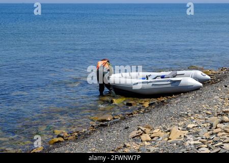 Inflatable rubber fishing boat on sandy beach near sea Stock Photo