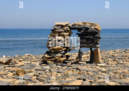 Intricately stacked flat stones in a pyramid on the seashore. Vacation by the sea. Selective focus. Stock Photo