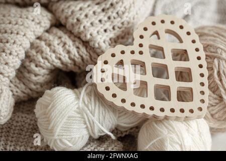Cozy composition with knitted items and a wooden decorative heart close up. Stock Photo