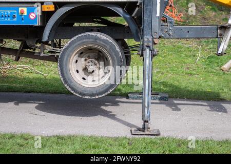 Close view of the rear wheels of a cherry picker truck raised off the ground using the hydraulic extendable legs to provide a stable foundation for th Stock Photo