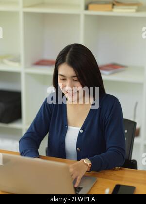 Portrait of female university student doing assignment with laptop in library Stock Photo