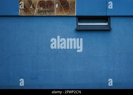 View of a blue house wall of a tram stop in Munich with a faded Langnese ice cream advertising sign. Stock Photo