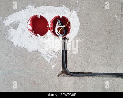 Electrical wires with cables at home repair. New electrical outlets. Socket on concrete wall Stock Photo