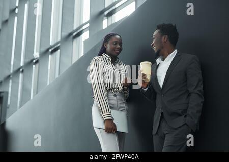 Low angle portrait of two African-American business people chatting in office hall, black and white pattern, copy space Stock Photo
