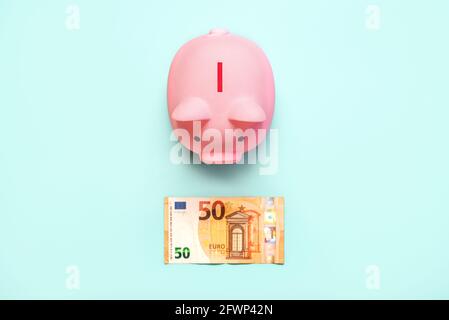 Top view of pink piggy money bank with euro bill on a blue background Stock Photo