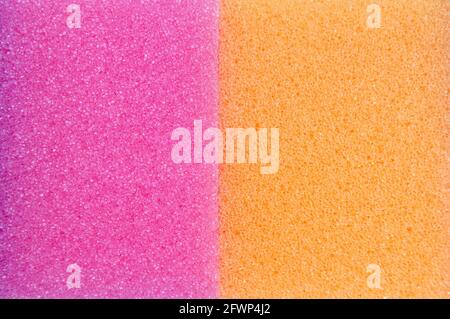 A Close Up Shot Of Two Washing Up Sponges, One Pink and One Orange, Next To Each Other Stock Photo