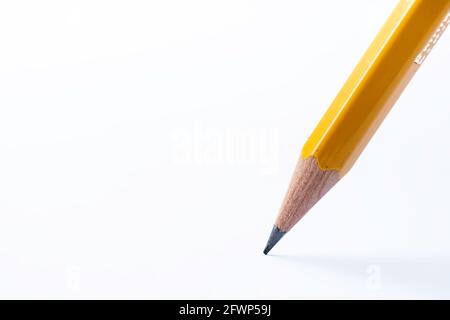 Pencil stands on white paper. The sharp point has just been sharpened. Focus on the black graphite tip. Background image Stock Photo