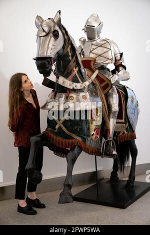 A Bonhams employee looks at a set of German late 16th century style equestrian full armour for a man and horse, which is estimated to fetch £15,000 - £20,000, during a preview for the forthcoming Antique Arms and Armour Sale, at Bonhams' London. Picture date: Monday May 24, 2021. Stock Photo