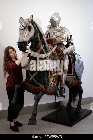 A Bonhams employee looks at a set of German late 16th century style equestrian full armour for a man and horse, which is estimated to fetch £15,000 - £20,000, during a preview for the forthcoming Antique Arms and Armour Sale, at Bonhams' London. Picture date: Monday May 24, 2021. Stock Photo