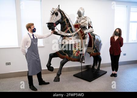 A Bonhams employee looks at a set of German late 16th century style equestrian full armour for a man and horse, which is estimated to fetch £15,000 - £20,000, during a preview for the forthcoming Antique Arms and Armour Sale, at Bonhams' London. Picture date: Monday May 24, 2021. Stock Photo