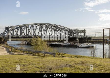 ZUTPHEN, NETHERLANDS - Apr 20, 2021: Steel train and traffic draw bridge over the river IJssel with a cargo ship passing by near the Dutch Hanseatic c Stock Photo