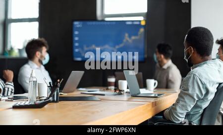 Diverse colleagues having meeting in boardroom, sitting at desk Stock Photo