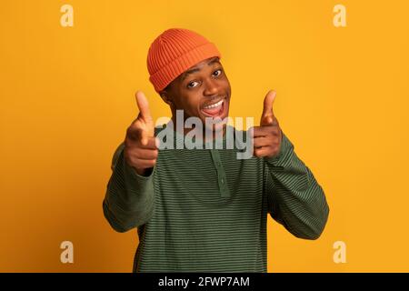 Gotcha. Cheerful black hipster guy pointing at camera with two hands Stock Photo