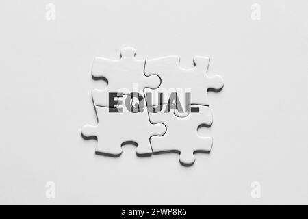 Jigsaw puzzle pieces connected to each other with the word equal. Equality, equal rights, payment or opportunity concept. Stock Photo