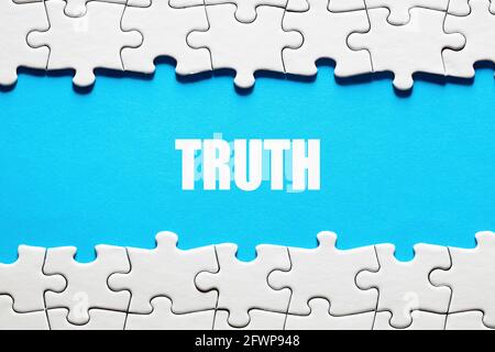 The word truth on blue background framed by jigsaw puzzle pieces. To discover or expose the truth, facts and reality concept. Stock Photo