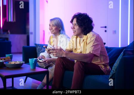 Photo of young couple playing video games at home at night. Stock Photo