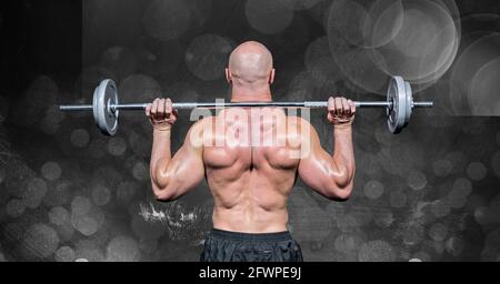 Composition of rear view of muscular man lifting weights with spot lights on black background Stock Photo