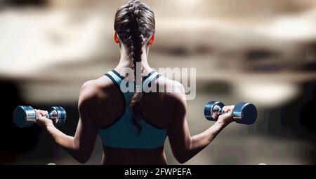 Composition of rear view of strong caucasian woman lifting dumbbells with copy space Stock Photo