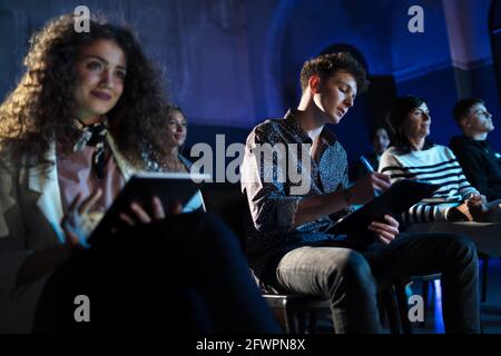 Group of people making notes while listening to presentation at conference. Stock Photo