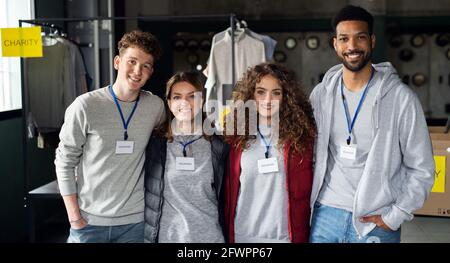 Group of volunteers at work in community charity donation center, looking at camera. Stock Photo