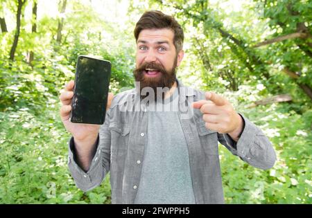 online everywhere. happy bearded man on phone. Mature hipster with beard pointing finger. got lost in forest. brutal man with phone. hipster style Stock Photo