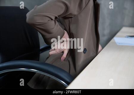 Midsection Of Business woman With Backache Sitting On Chair In Office. Stock Photo