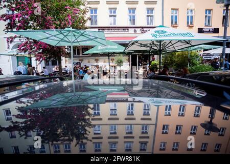 Berlin, Germany. 24th May, 2021. Parasols of a burger restaurant in Berlin's Prenzlauer Berg district are reflected in a car roof. Credit: Christoph Soeder/dpa/Alamy Live News Stock Photo