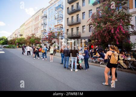 Berlin, Germany. 24th May, 2021. Guests stand in a long queue outside an ice cream parlour in the Prenzlauer Berg district of Berlin. Credit: Christoph Soeder/dpa/Alamy Live News Stock Photo