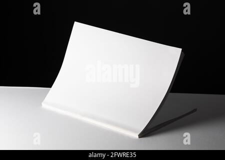 Composition of half opened book with blank pages on black and white background Stock Photo