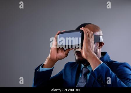 African american businessman wearing vr headset against grey background Stock Photo