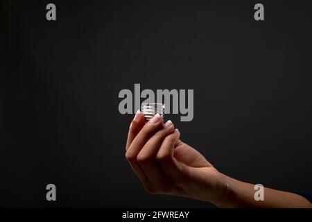 Close up of hand holding bulb screw base against black background Stock Photo