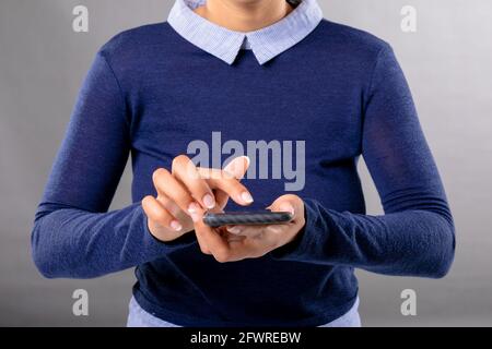 Mid section of african american businesswoman using smartphone against grey background Stock Photo