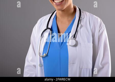 Mid section of african american female doctor smiling against grey background Stock Photo