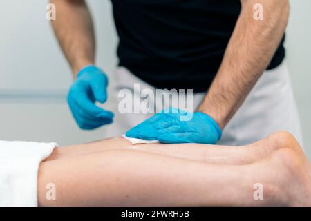 Unrecognized medic worker doing acupuncture procedure to female client in physiotherapy clinic. Stock Photo