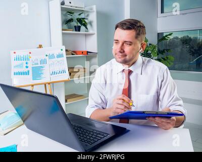 Smiling manager makes notes during online communication. New normal concept. Stock Photo