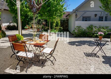 05.15.2021- Koveskal, Hungary: Vintage Outdoor table in a garden with setting and flowers Stock Photo