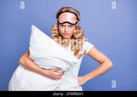 Portrait of attractive moody grumpy wavy-haired woman holding pillow bedtime isolated over blue pastel color background Stock Photo