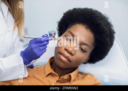 Non-injectable mesotherapy, skin revitalizaion, oxygen peeling concept. Closeup portrait of lovely african young woman getting oxygen skin care therapy in a beauty salon Stock Photo