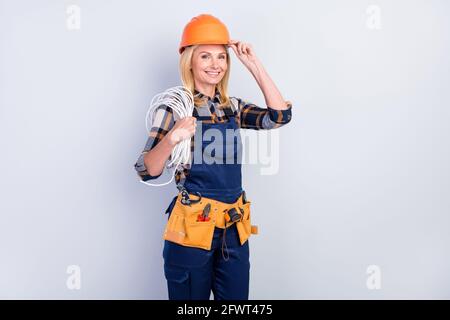Photo of cheerful blond hair lady hold cabel wear cap shirt work overall isolated on grey color background Stock Photo