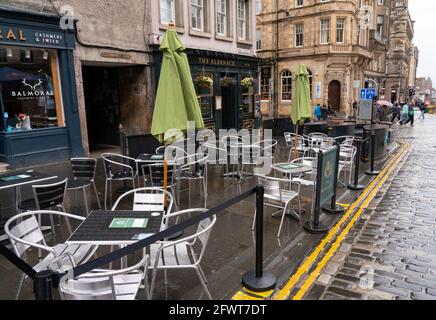 Scotland, Scotland, UK. 24 May 2021. Unseasonable cool and damp weather in Edinburgh meant that there were few customers in the many outdoor bars , cafes and restaurants in the city centre, With few tourists in the capital the streets remain much quieter than normal. Pic; Outdoor seating for bars and restaurants lie empty at lunchtime on the Royal Mile. Iain Masterton/Alamy Live News Stock Photo