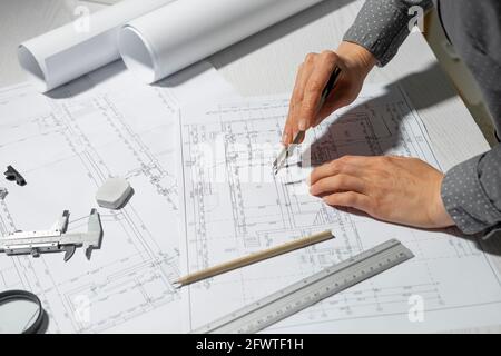 The architect measures with a dividers for drawing on paper. The designer draws a sketch of the project of the room. Stock Photo
