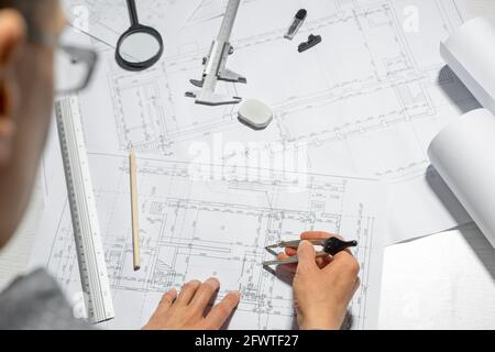 The architect measures with a dividers for drawing on paper. The designer draws a sketch of the project of the room. Stock Photo
